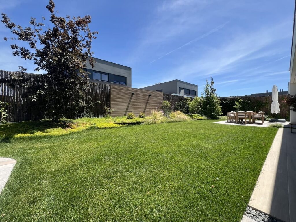 Césped natural y parterre con gramíneas ornamentales en jardín de vivienda unifamiliar en Villalbilla, Madrid — Abierto al Jardín
