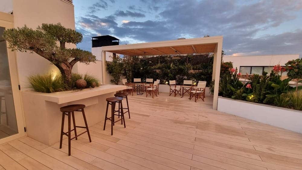 Pérgola de madera con barra exterior y zona de estar en ático en Castellana, Madrid — Abierto al Jardín