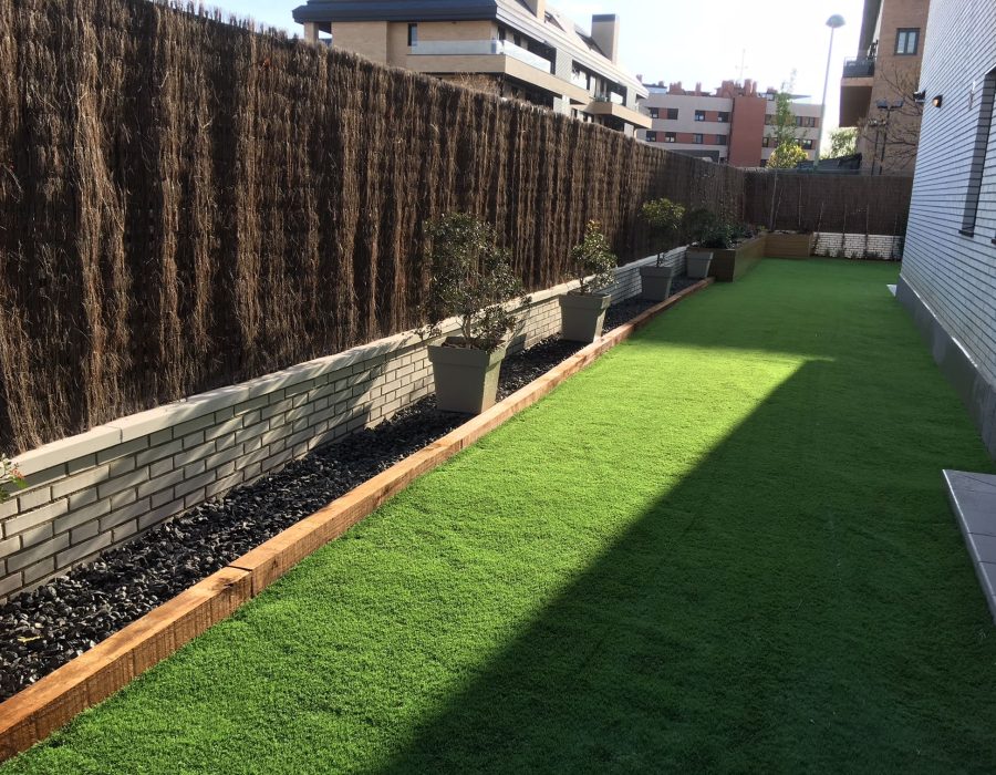 Borde de jardín con macetas de olivo junto a césped artificial en Pozuelo de Alarcón — Abierto al Jardín