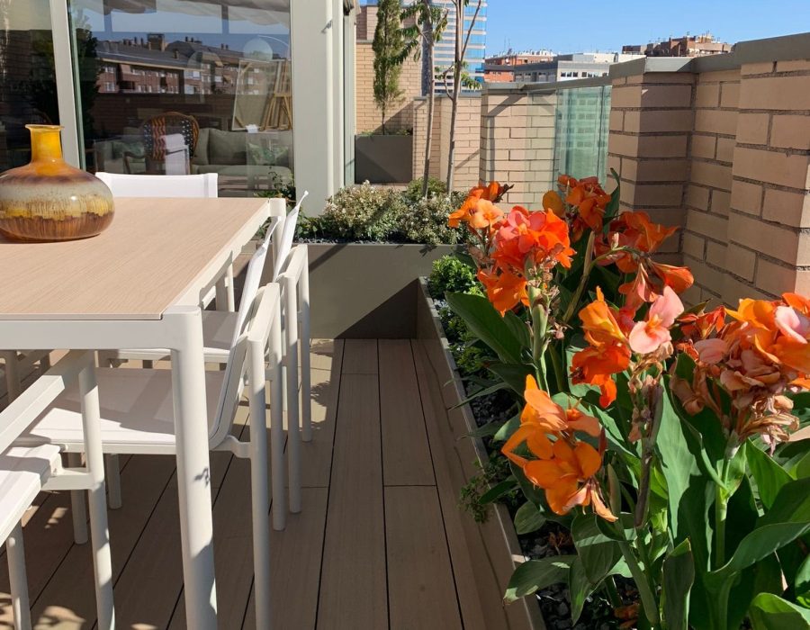 Comedor exterior acristalado junto a jardinera florida en ático en Puerta de Hierro, Madrid — Abierto al Jardín