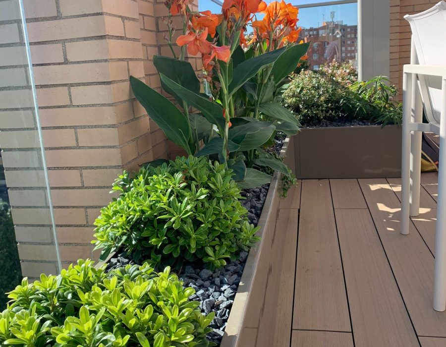 Jardinera con cañas naranjas junto a pilar de ladrillo en ático en Puerta de Hierro, Madrid — Abierto al Jardín