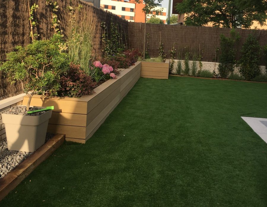 Jardinera de composite con hortensias, gramíneas y trepadoras junto a césped artificial en Pozuelo, Madrid — Abierto al Jardín