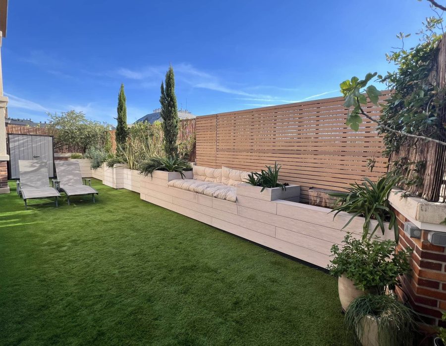 Vista general de jardín en bajo con banco, jardineras de composite, panel de lamas y cipreses en Majadahonda — Abierto al Jardín