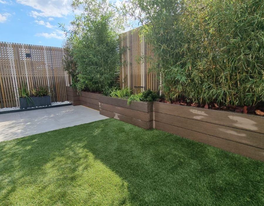 Zona de estar junto a césped artificial y jardinera de bambú en Boadilla del Monte — Abierto al Jardín
